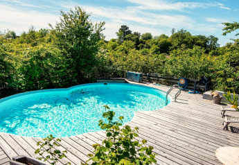 Piscine extérieure avec terrasse en bois entourée de verdure au gîte 8 personnes à Ebeltoft, Danemark.