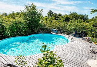 Außenpool mit Holzterrasse inmitten grüner Natur beim 8-Personen-Ferienhaus in Ebeltoft, Dänemark.