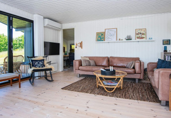 Lichte woonkamer in een vakantiehuis in Ebeltoft, Denemarken, met lederen banken en grote ramen.