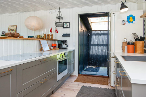 Moderne keuken in een vakantiehuis in Ebeltoft, Denemarken, met grijze kasten en open deur naar buiten.