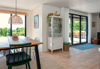 Salle à manger lumineuse d'une maison de vacances pour 8 personnes à Ebeltoft, Danemark, avec grandes fenêtres.