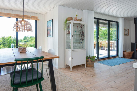 Lichte eetkamer in een 8-persoons vakantiehuis in Ebeltoft, Denemarken, met grote ramen en houten meubels.