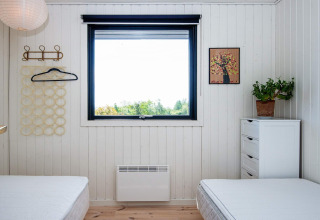 Room with two beds, a window view, white dresser, potted plant, and wall art in a holiday home in Ebeltoft.
