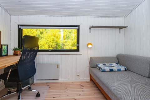 Zona lavoro e relax moderna con grande finestra, scrivania, sedia e divano letto a Ebeltoft, Danimarca.