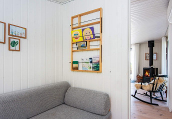 Living room in a holiday home in Ebeltoft with a grey sofa, wall art, and a fireplace in view.