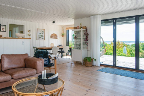 Wohnzimmer eines Ferienhauses in Ebeltoft, Dänemark, modern eingerichtet mit großen Fenstern und Ausblick.
