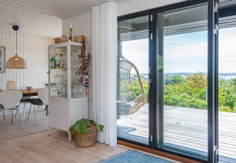 Woonkamer in vakantiewoning Ebeltoft met glazen schuifdeuren, hangstoel en eethoek.
