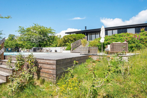 Zonnig houten terras met zwembad en zitmeubels bij vakantiehuis voor 8 personen in Ebeltoft, Denemarken