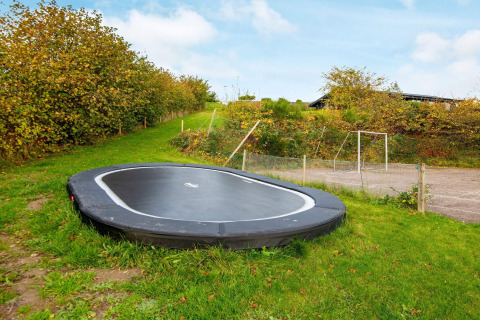Trampoline enterré sur pelouse verte près d'une maison de vacances 8 personnes à Ebeltoft, Danemark.