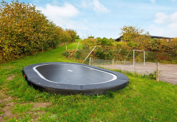 Ingegraven trampoline bij een 8-persoons vakantiehuis in Ebeltoft, Denemarken, met groene tuin.