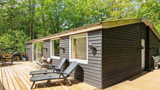 Terrasse eines 5-Personen-Ferienhauses in Ans By mit schwarzen Liegestühlen, Natur und Bäumen.
