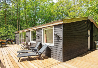 Terrasse eines 5-Personen-Ferienhauses in Ans By mit schwarzen Liegestühlen, Natur und Bäumen.