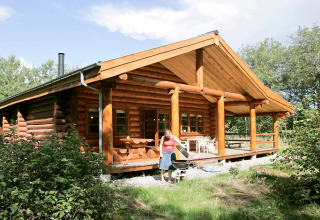 Persoon aan het barbecueën voor een blokhut met veranda in het 10-persoons vakantiehuis in Hadsund, Denemarken.