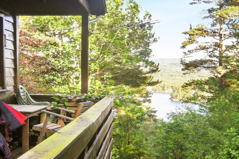 Uitzicht vanaf het terras van een lodge in Reksteren, Denemarken, met stoelen en zicht op meer en bos.