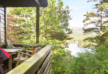 Vista dal balcone di una casa vacanze a Reksteren, Danimarca, con sedie e paesaggio di lago e bosco.