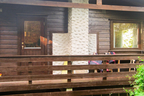 Facciata di casa in legno con camino bianco, terrazza e ringhiera presso casa vacanze Reksteren, Danimarca.