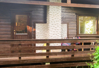 Facciata di casa in legno con camino bianco, terrazza e ringhiera presso casa vacanze Reksteren, Danimarca.