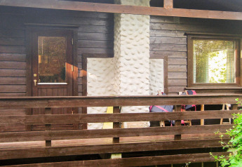 Facciata di casa in legno con camino bianco, terrazza e ringhiera presso casa vacanze Reksteren, Danimarca.