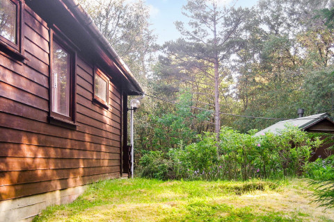 Houten lodge met tuin en bos op de achtergrond, vakantiehuis in Reksteren, Denemarken.
