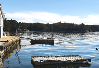 Aussicht vom Ferienhaus in Reksteren, Dänemark, mit Holzsteg und schwimmenden Plattformen im Wasser.