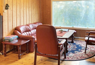 Wohnzimmer im Ferienhaus in Reksteren, Dänemark, mit roten Ledermöbeln, Teppich und großem Fenster.