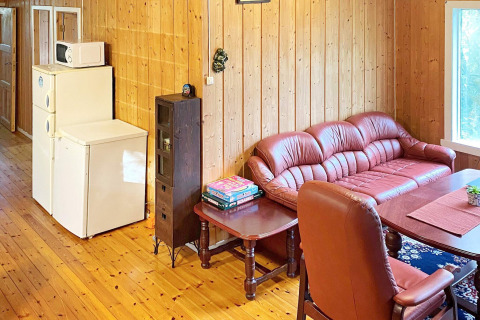 Woonkamer in vakantiehuis in Reksteren, Denemarken met leren bank, tafel, koelkast en gezelschapsspellen.