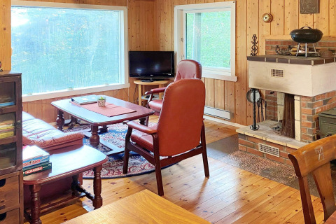 Knusse houten woonkamer met haard, lederen stoelen, groot raam en gezelschapsspellen in Reksteren.