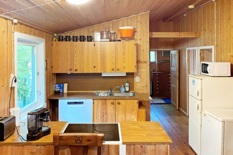 Cocina revestida de madera en casa de vacaciones en Dinamarca, con electrodomésticos y ventana luminosa.