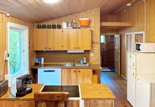Houten keuken in een vakantiewoning te Reksteren, Denemarken, met apparatuur en heldere raamlicht.