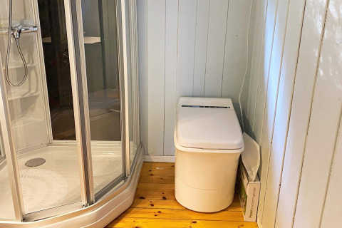 Badkamer in vakantiehuis in Reksteren met glazen douchecabine en modern toilet op houten vloer.