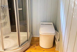 Modernes Badezimmer in einem Ferienhaus in Reksteren mit Dusche und Hightech-Toilette auf Holzboden.