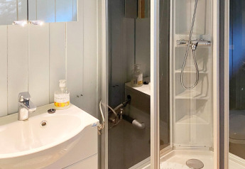 Moderne badkamer in een vakantiewoning in Reksteren, Denemarken, met wasbak, spiegel en douchecabine.