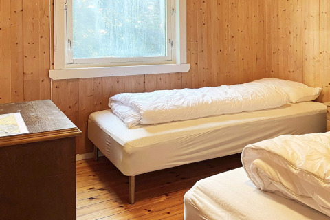 Slaapkamer met twee eenpersoonsbedden, houten wanden en raam in een vakantiehuis in Reksteren, Denemarken.