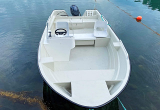 Kleine motorboot voor vier personen bij een vakantiehuis in Reksteren, Denemarken, rustig water.