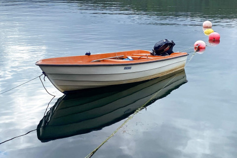 Kleine roeiboot met buitenboordmotor, vastgemaakt op stil water naast boeien, genomen bij Reksteren lodge.