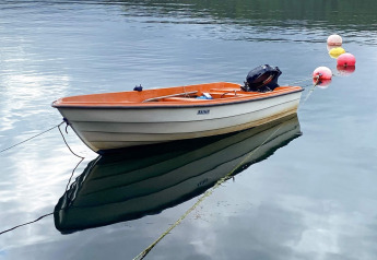 Petite barque à moteur attachée sur eau calme près de bouées, photo près du lodge de Reksteren.