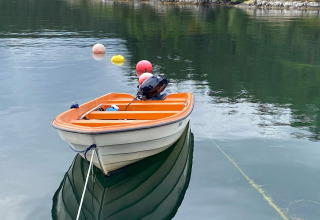 Kleine oranje-witte roeiboot op rustig water bij een 4-persoons vakantiehuis in Reksteren, Denemarken.