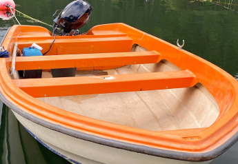 Piccola barca a motore arancione ormeggiata vicino alla casa vacanze per 4 persone a Reksteren, Danimarca.