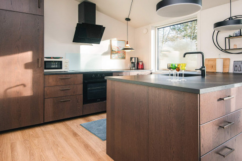 Cocina moderna con gabinetes de madera, isla, gran ventana y luz natural en Ans By, Dinamarca.