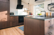Cocina moderna con gabinetes de madera, isla, gran ventana y luz natural en Ans By, Dinamarca.
