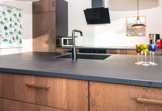 Cucina moderna in casa vacanze ad Ans By, Danimarca, con piano scuro e bicchieri colorati sull'isola.