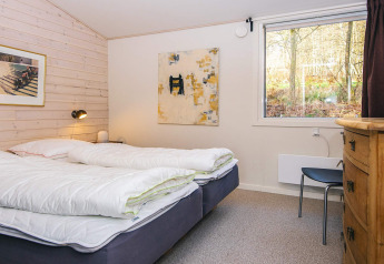 Chambre d'une maison de vacances à Ans By, Danemark, avec deux lits, tableaux et vue sur la nature.