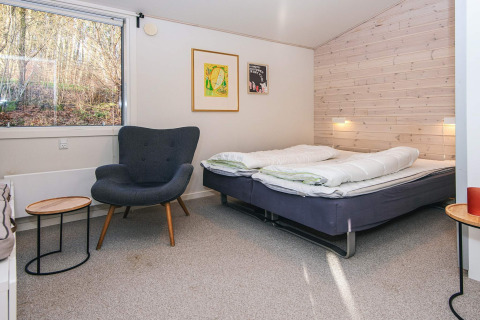 Modernes Schlafzimmer in einer Lodge mit Doppelbett, Sessel, Wandkunst und großem Fenster in Ans By, Dänemark.