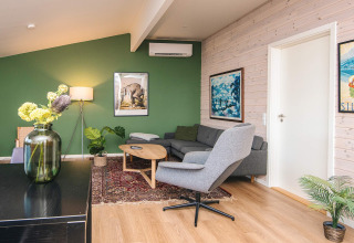 Acogedora sala de estar en casa vacacional en Ans By, Dinamarca, con pared verde y decoración moderna.