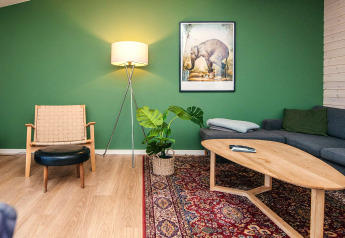 Salon de maison de vacances à Ans By, Danemark, avec mur vert, meubles modernes et tapis coloré.