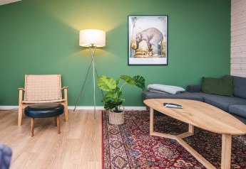 Sala de estar en casa de vacaciones en Ans By, Dinamarca, con pared verde, muebles modernos y alfombra.
