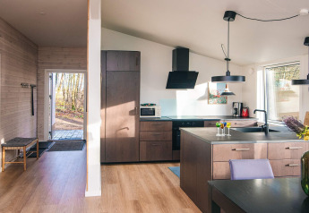 Cocina moderna y entrada de casa vacacional para 5 personas en Ans By, Dinamarca, con mucho sol y madera.
