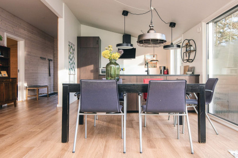Sala da pranzo e cucina moderne in una casa vacanze ad Ans By, Danimarca, con ampie finestre.