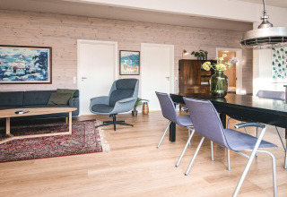 Salón elegante en casa de vacaciones en Ans By, Dinamarca, con mesa de comedor, sofá y hermosa decoración.