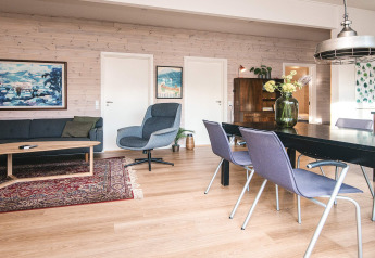 Stilfuldt opholdsrum i feriehus i Ans By, Danmark, med spisebord, sofa, lænestol og hyggelig indretning.